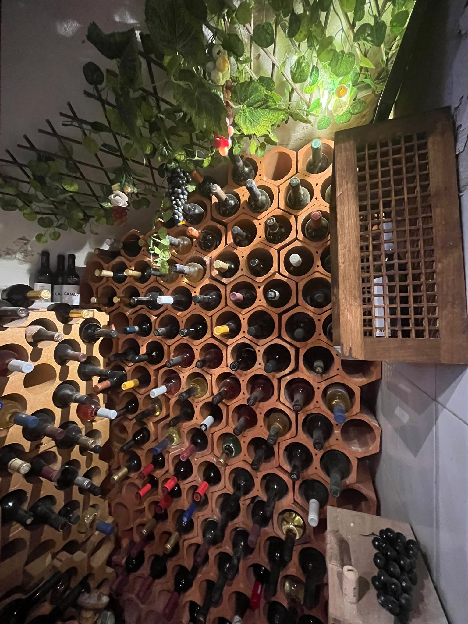 Parede decorada com garrafas de vinho regional, azulejos e quadros
